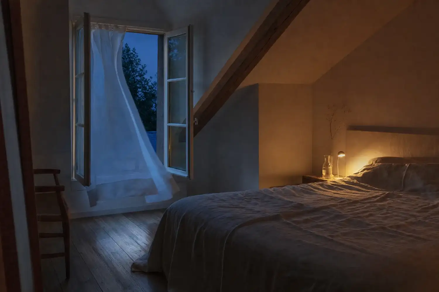 Fenêtre grande ouverte sur la nuit d'été pour rafraîchir une chambre mansardée avant le coucher, drap de lin léger sur le lit